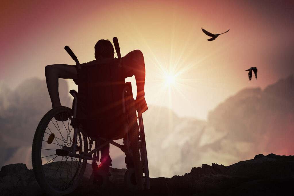 Man in Wheelchair triumphantly sits atop a hill watching the sunset. Chronic illness does not have to define you. Chronic illness counseling can help you rediscover who you are in the midst of your illness.