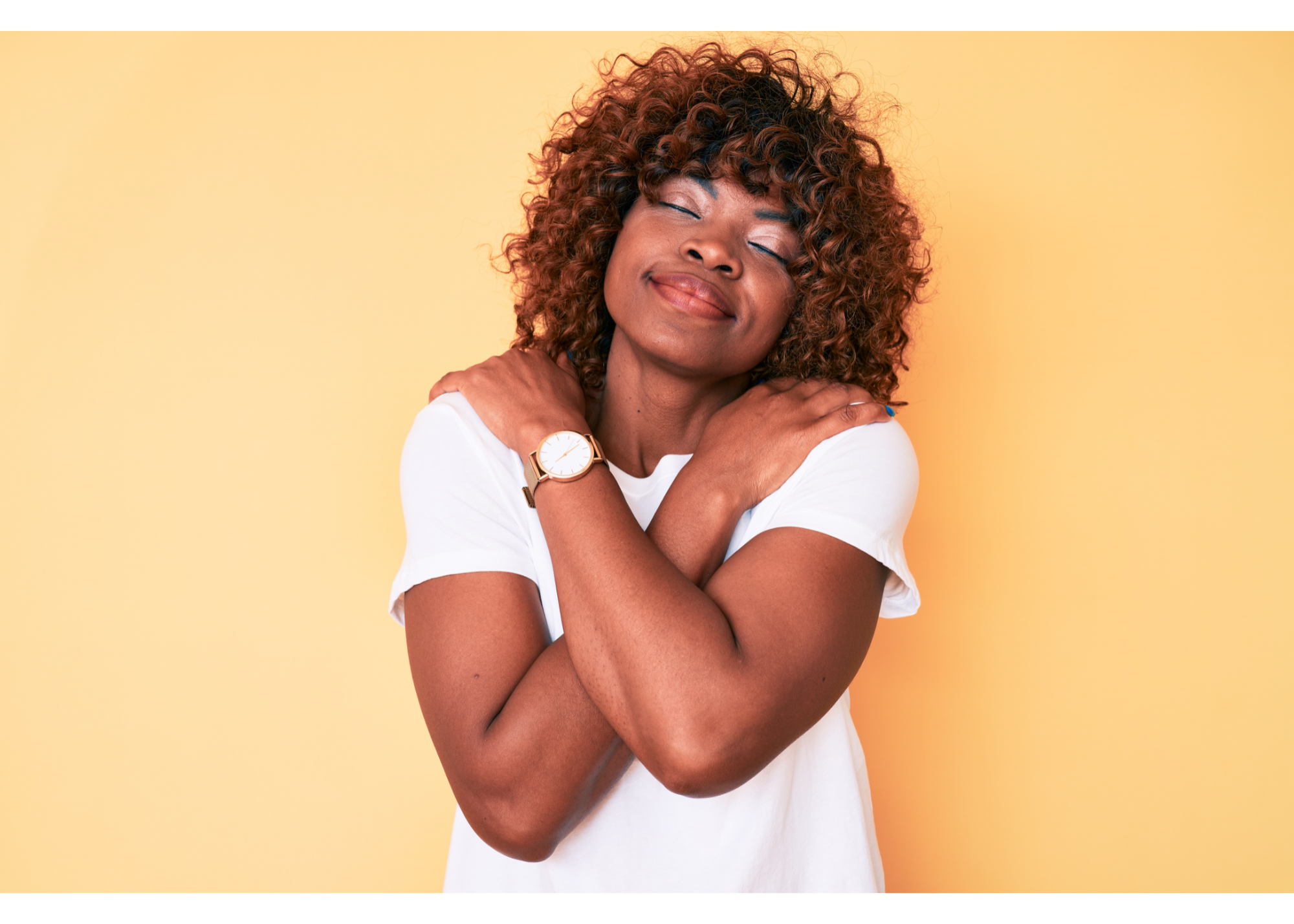 A woman smiles while hugging herself. This could represent the self-care cultivated by working with a New Bern therapist. They can offer therapy for anxiety in New Bern, NC, and other services including trauma therapy. 