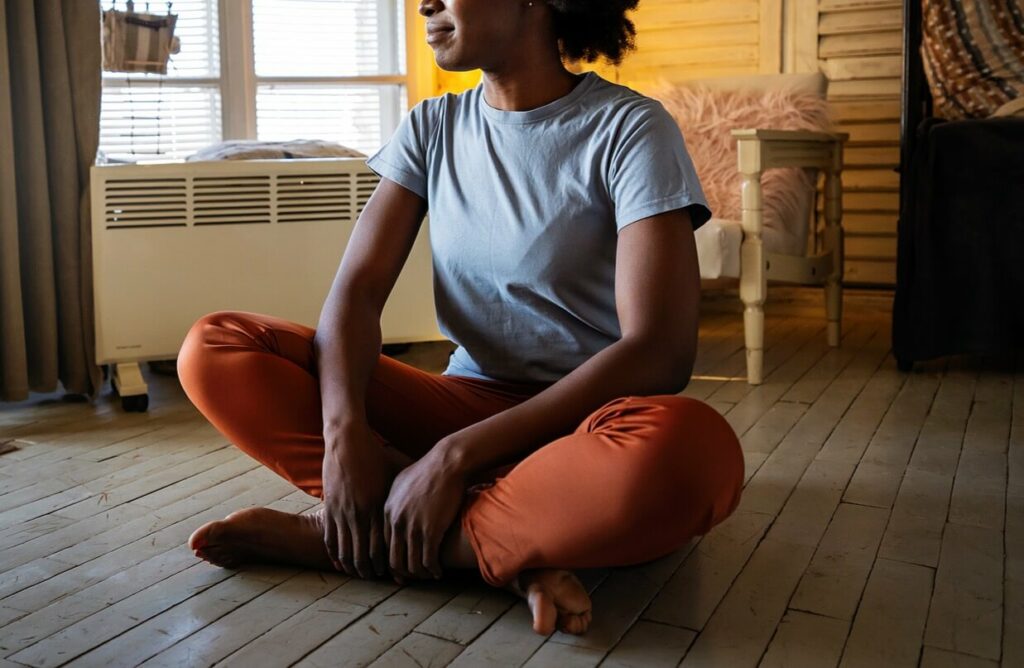 A woman sits on the floor while taking in the environment around her. This could represent how mindfulness can support mental wellness in North Carolina. Search “therapist new bern nc” to learn more about the support life changes counseling in North Carolina can offer today.  