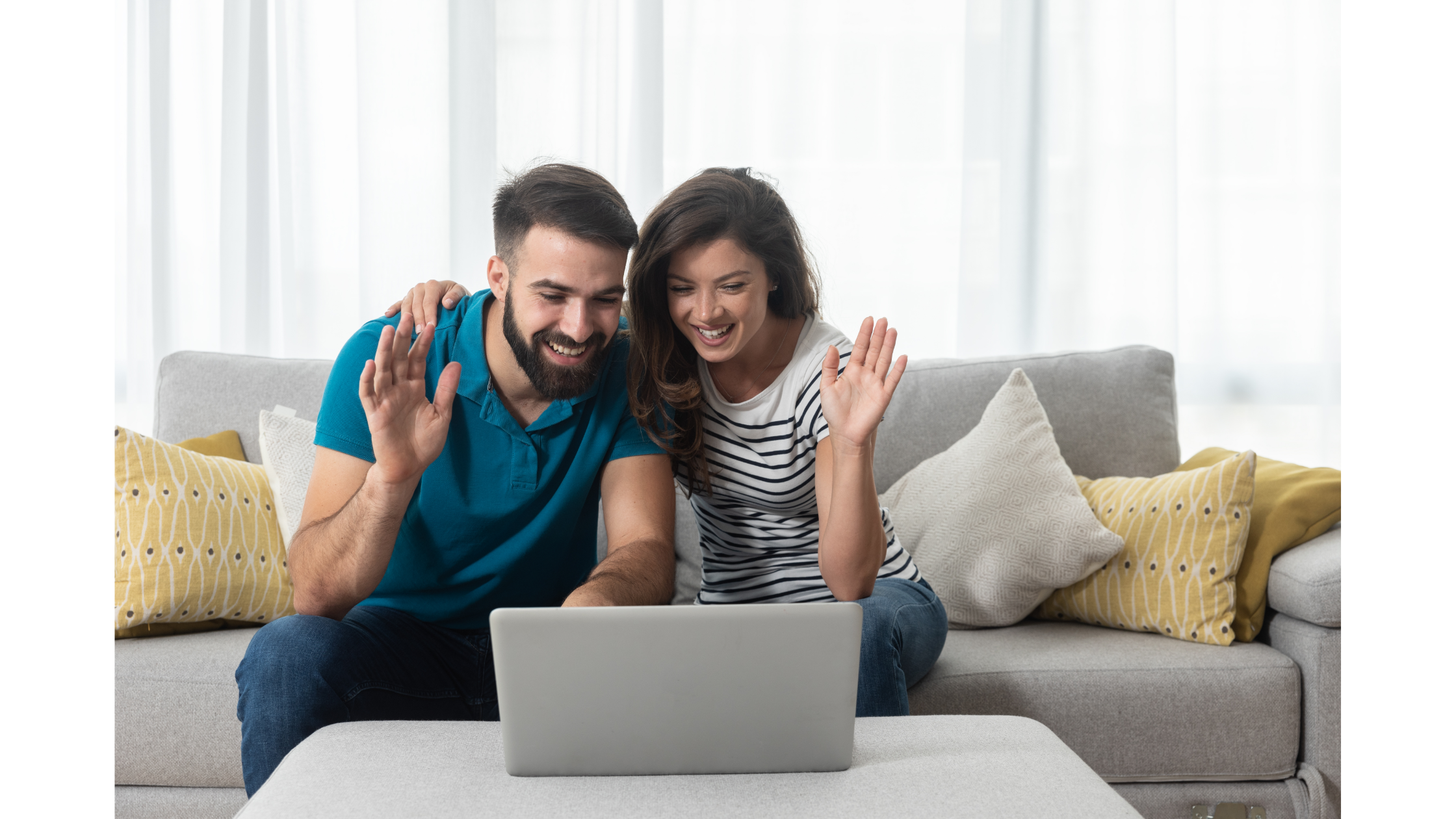 A couple wave at the laptop while sitting together on a couch. This could represent meeting with an online therapist in North Carolina from home. Learn more about online therapy in North Carolina and the support an online therapist can offer. 