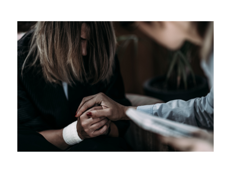 A close-up of a person holding the hands of a woman hanging her head. This could represent the support offered by a trauma therapist in New Bern, NC. Contact a therapist in New Bern, NC to learn more about trauma therapy in New Bern, NC, and more.