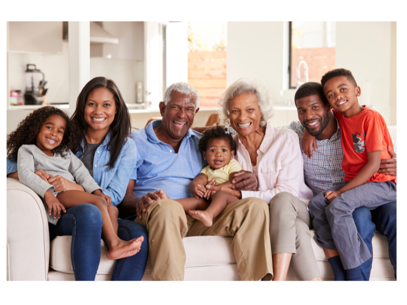 A multigenerational family smile for a picture on a sofa. This could symbolize the family bonds that can support new parents in New Bern, NC. Contact a New Bern therapist to learn more about anxiety treatment in New Bern, NC and other services. 