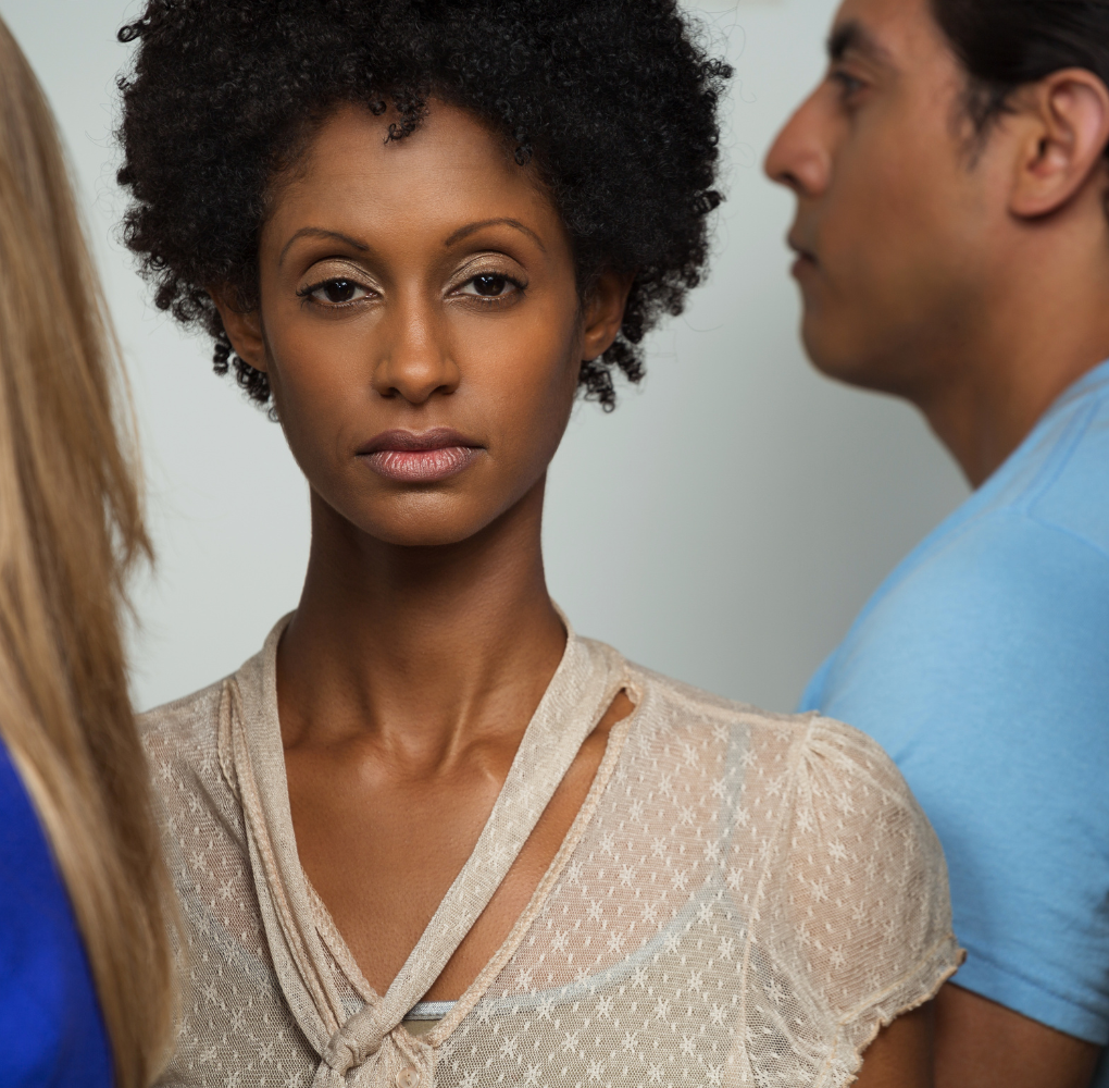 A woman stands looking toward the camera as other people face to the left. Learn how a New Bern therapist can offer support in overcoming anxious symptoms. Learn more about anxiety treatment in New Bern, NC and other services today. 