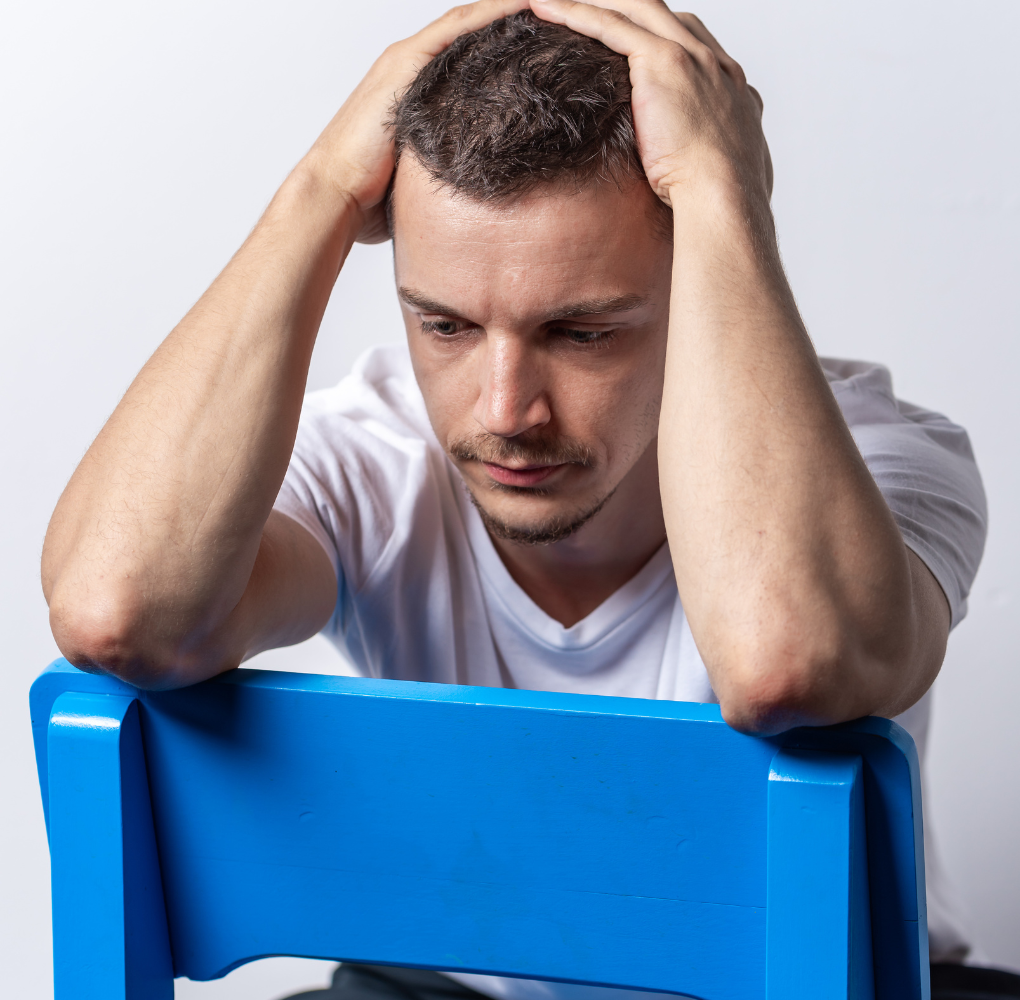A man sits with his hands on his head with a bleak expression. Learn how anxiety treatment in New Bern, NC can offer support for addressing symptoms. Contact a New Bern therapist to learn more about the support therapy for anxiety and stress in New Bern, NC can offer.