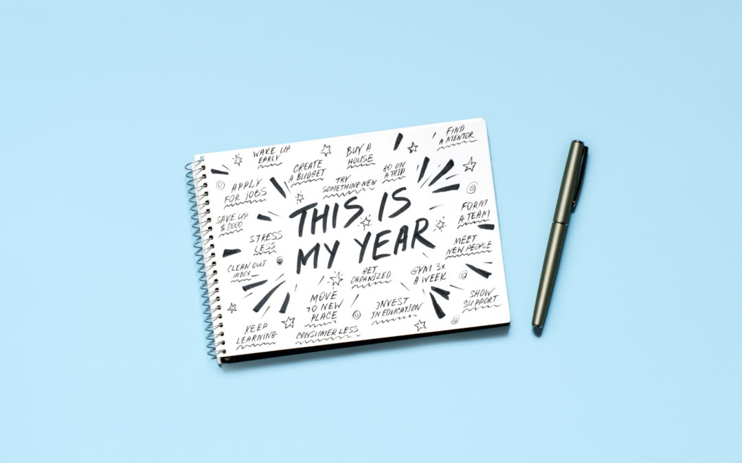 notebook with "This is My Year" written on it. Blue background with black pen.