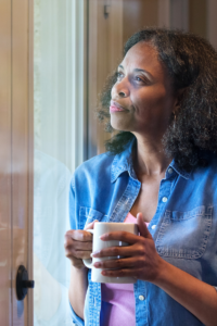 African American woman sipping coffee looking out window. Self-reflection counseling. 28562