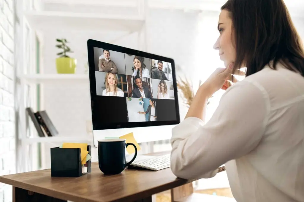 Woman attending a virtual team meeting on a desktop computer in a home office setting