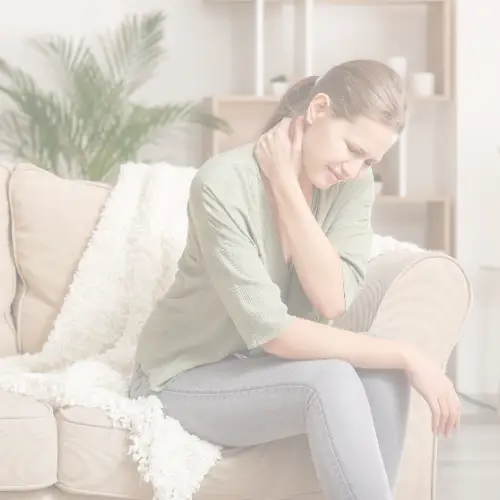Woman sitting on couch, holding neck in pain