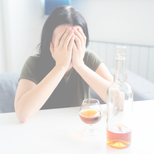 Woman with head in hands, alcohol in front of her