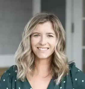 Alyssa Hermanson, LCSW therapist at Renewed Wellness Counseling, smiling in front of a gray and white building, wearing a green blouse with light polka dots.