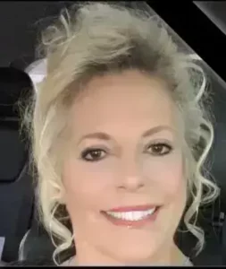 Rhonda Dunning, LCMHC therapist at Renewed Wellness Counseling, smiling with curled hair in bright car interior.