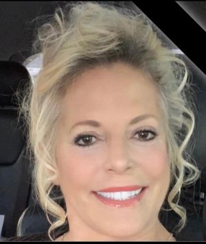 Rhonda Dunning, LCMHC therapist at Renewed Wellness Counseling, smiling with curled hair in bright car interior.