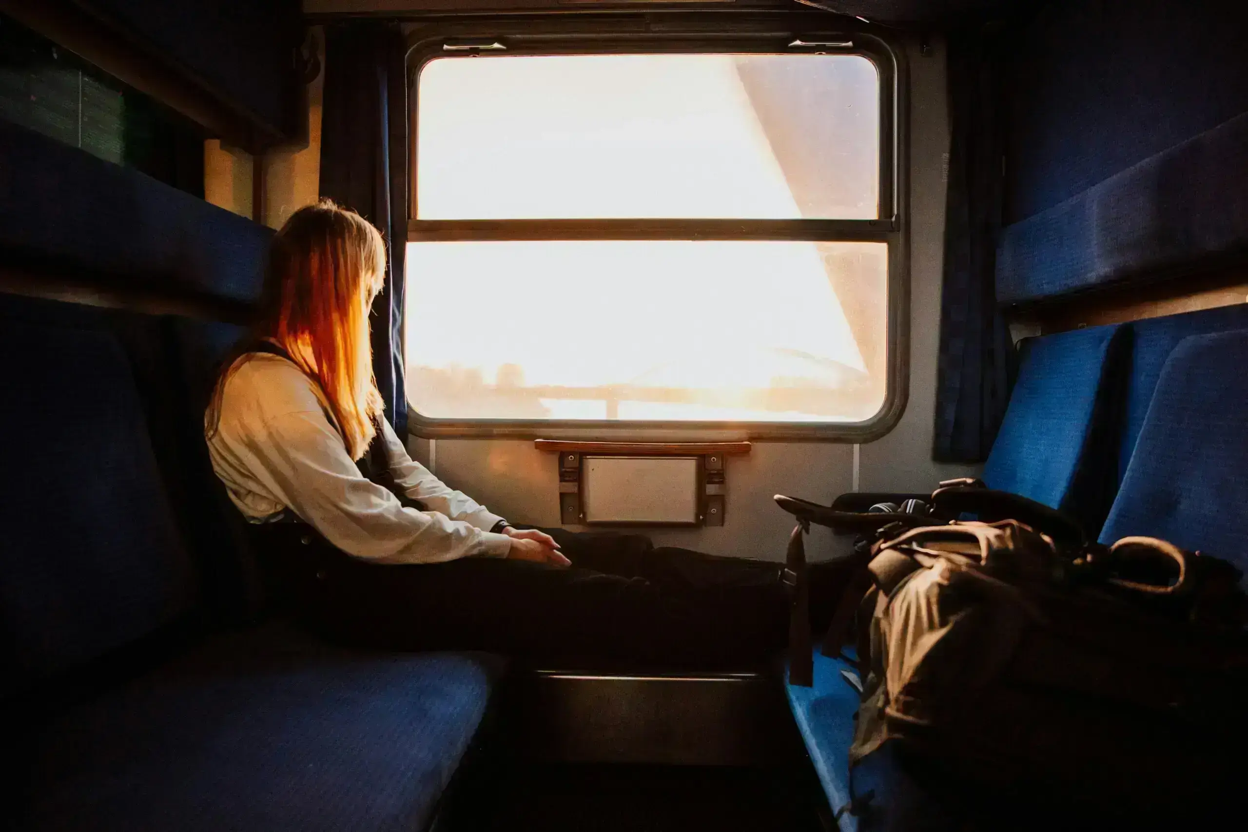 Woman on a train looking out at sunset — symbolizing healing from past trauma, emotional reflection, and inner peace.