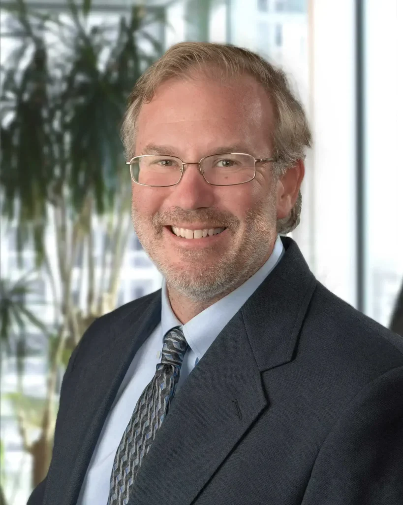 Rob Heubel, LMFT at Renewed Wellness Counseling, smiling in a suit and tie with glasses, office background behind him.