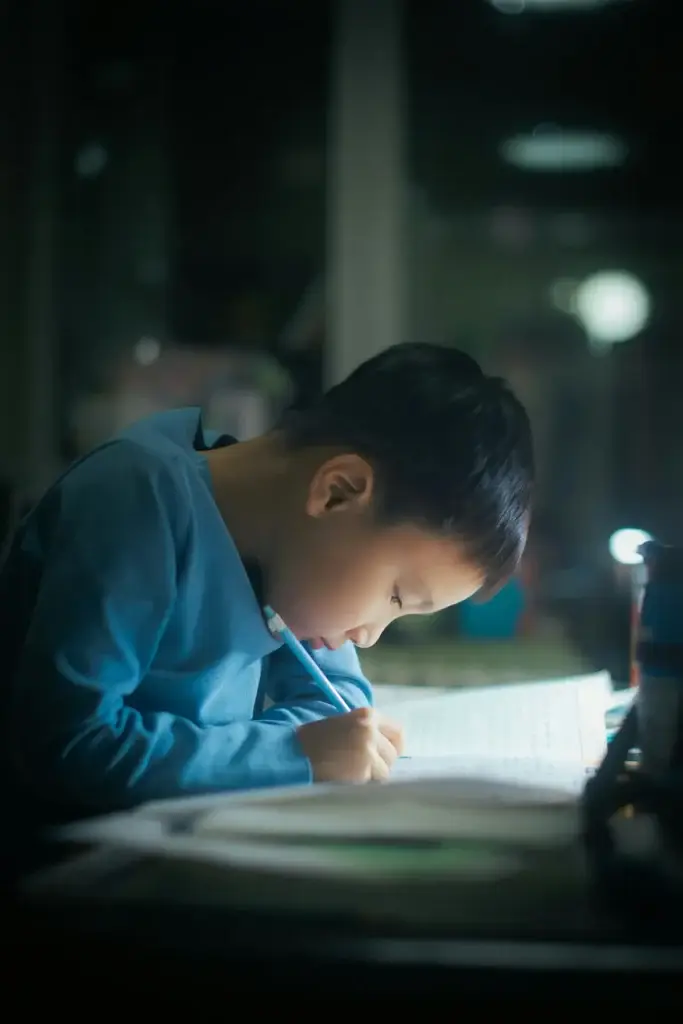 Elementary school-aged boy focused on writing at his desk