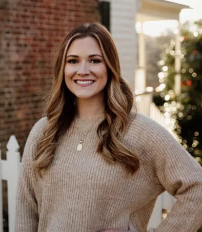 Kaitlyn Moore, LCSW, therapist at Renewed Wellness Counseling, smiling outdoors in a beige sweater.