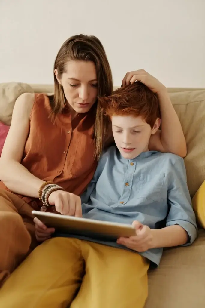 Mother and son sitting on a couch looking at a tablet together