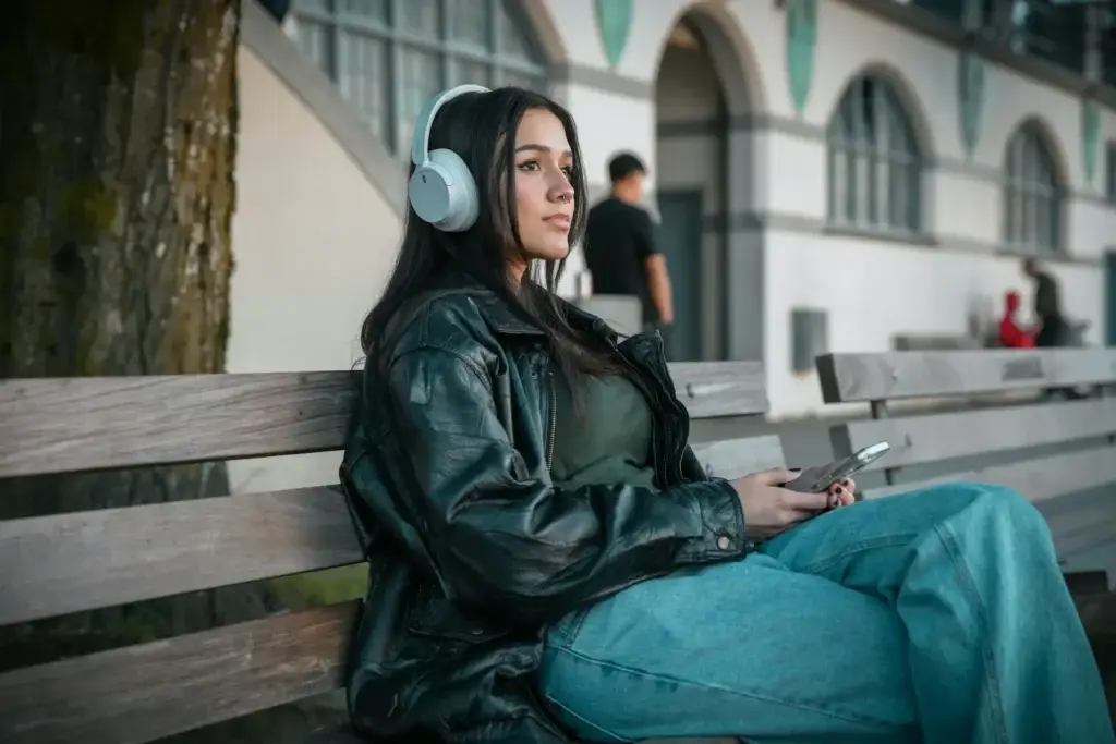 Teen girl sitting on a bench with headphones, reflecting quietly