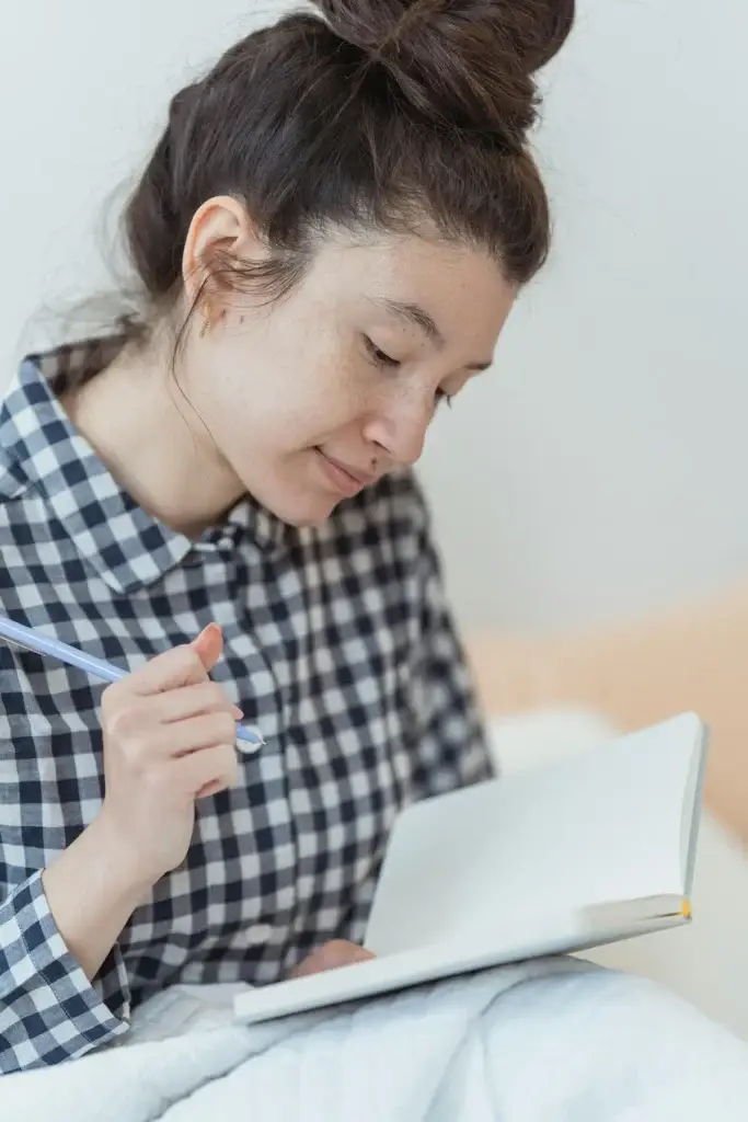 Woman sitting with a journal in her lap, writing thoughtfully
