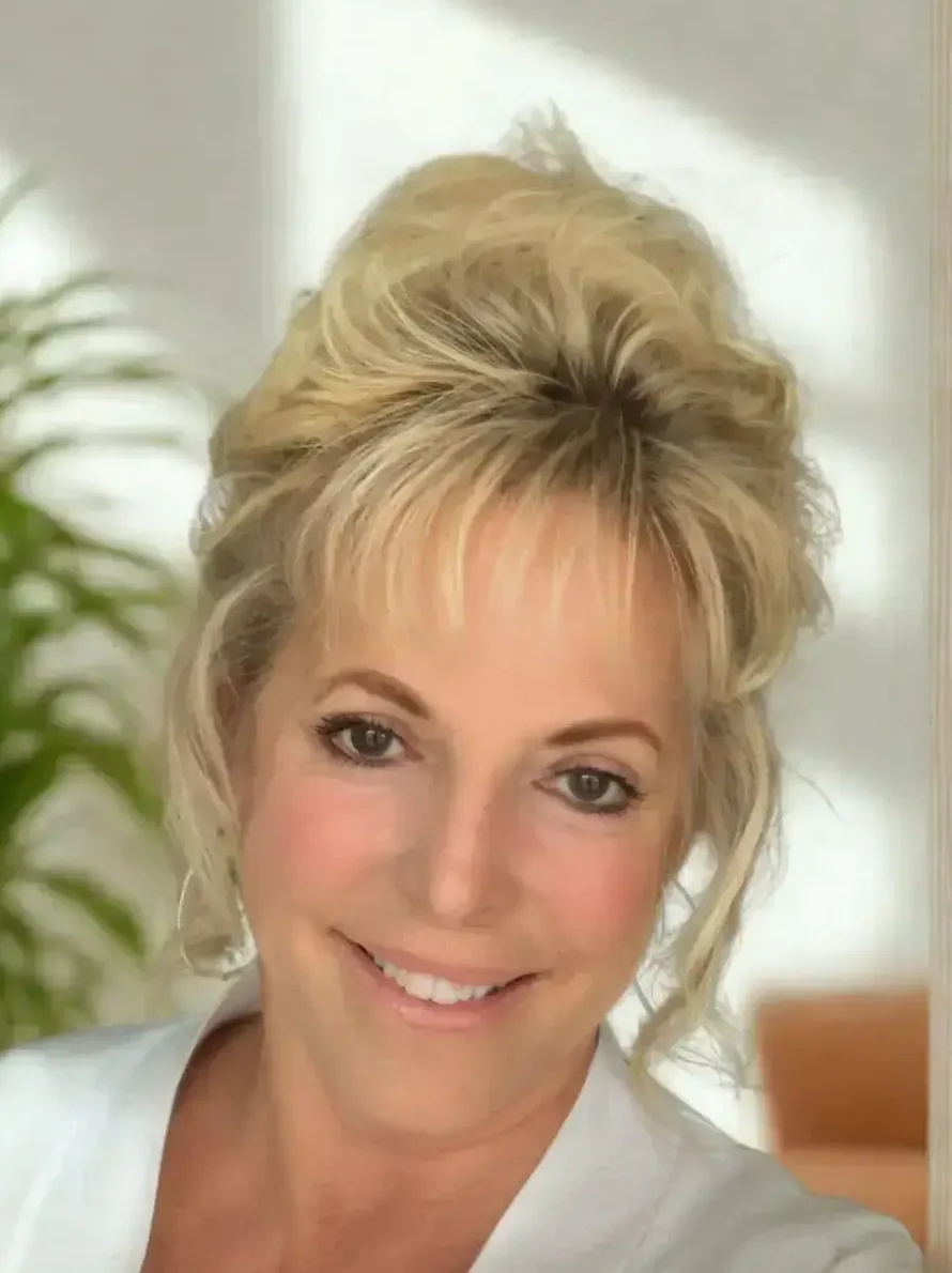 Rhonda Dunning, LCMHC therapist at Renewed Wellness Counseling, smiling with hair up in bright office space interior.