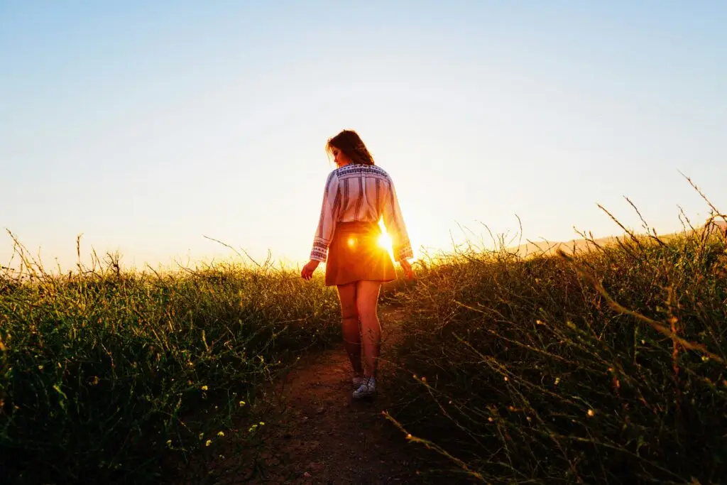 Woman walking alone on a path at sunset, symbolizing change, reflection, and navigating major life transitions.