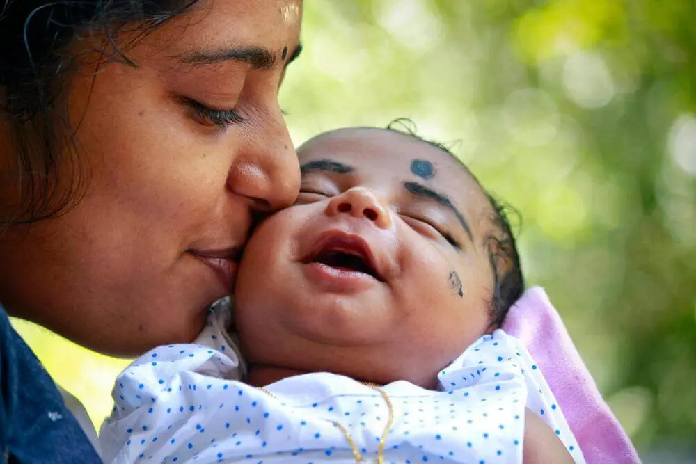 Image of mom kissing her baby finding peace and healing in her postpartum period
