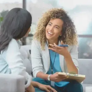 Therapist smiling and talking with a new client during their first therapy session, helping them feel comfortable and understood.