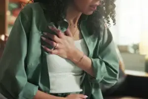 Woman holding chest representing chest tightness and physical symptoms of anxiety – therapy in New Bern NC