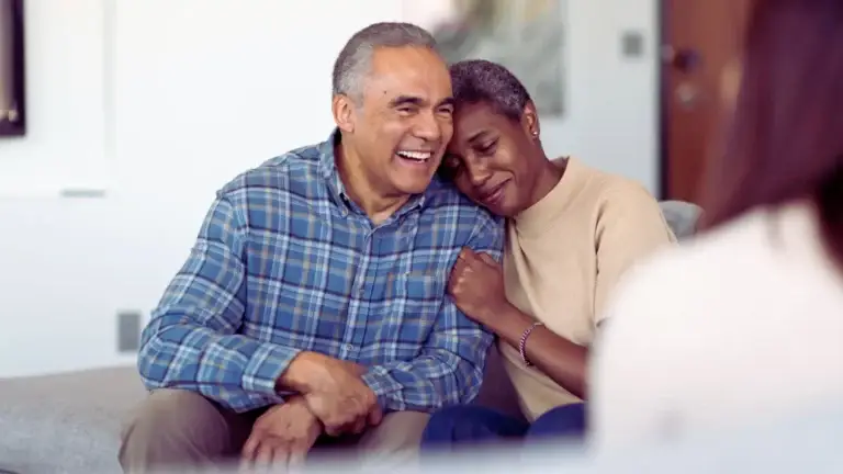 Couple sitting close together smiling and leaning on each other, showing emotional connection and healing after therapy