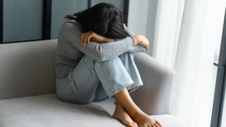 Woman sitting alone with her head down while feeling emotionally overwhelmed