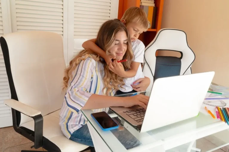 Mom working on a laptop while her child leans over her shoulder