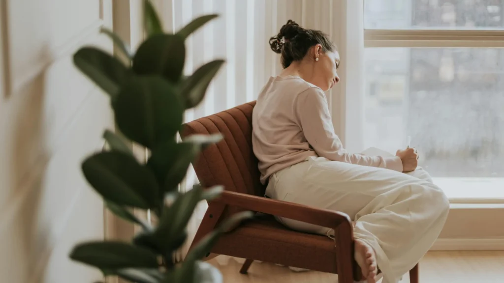 Woman sitting by a window and writing in a notebook
