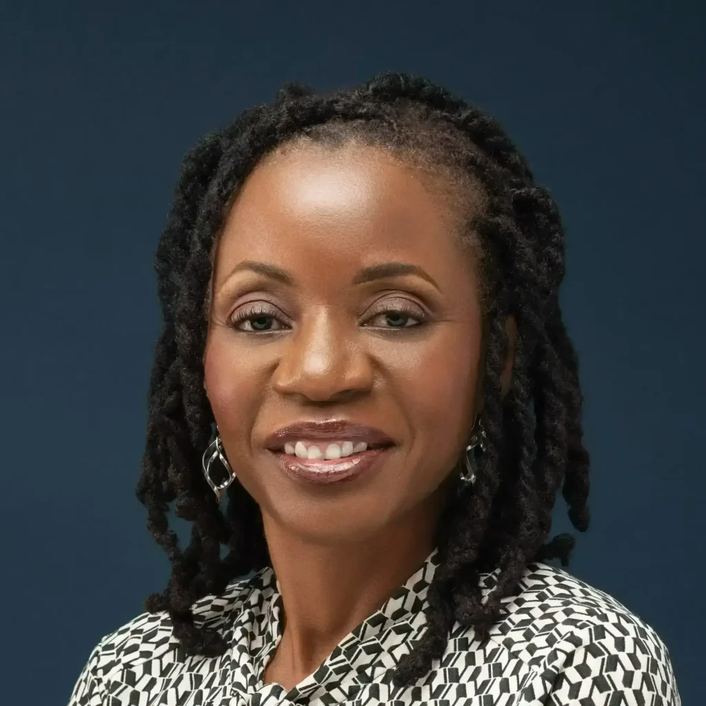 Olayinka Dykes, LCMHC therapist at Renewed Wellness Counseling, smiling in front of a dark blue background.