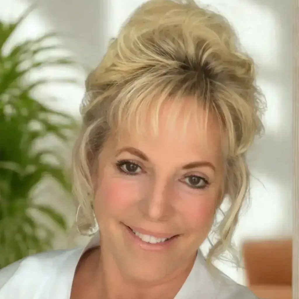 Rhonda Dunning, LCMHC therapist at Renewed Wellness Counseling, smiling with hair up in bright office space interior.
