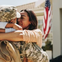 Military service member hugging family during homecoming, representing support for veterans, active-duty military, and their families.