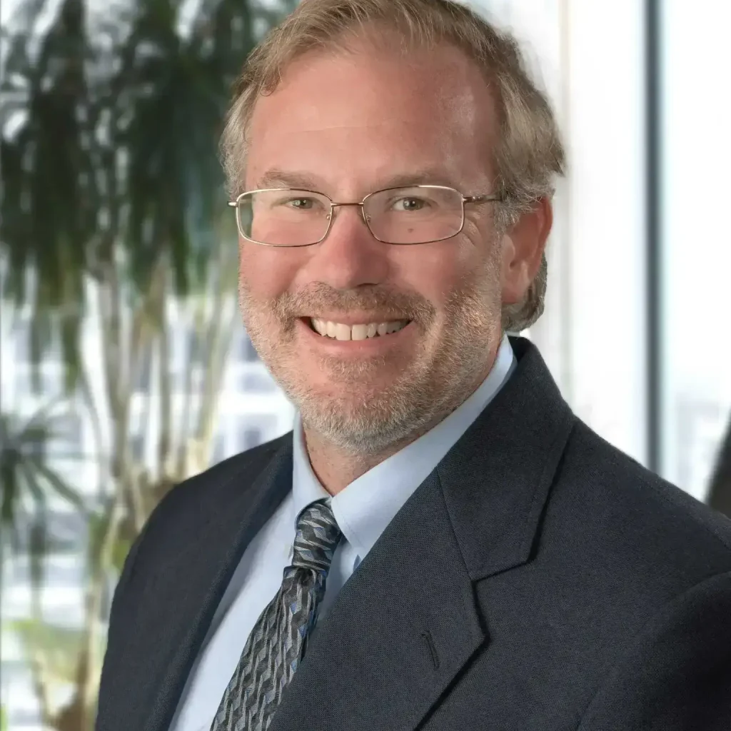 Rob Heubel, LMFT at Renewed Wellness Counseling, smiling in a suit and tie with glasses, office background behind him.