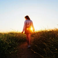 Woman walking alone on a path at sunset, symbolizing change, reflection, and navigating major life transitions.
